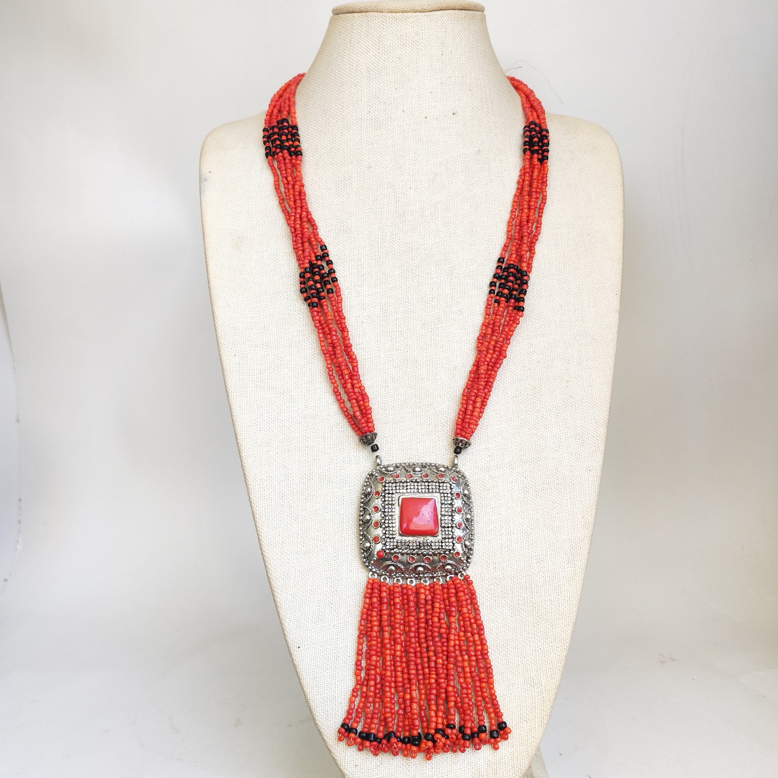 Vintage Red Faux Coral Beaded Necklace with Silver Tone Pendant and Tassel detail photograph