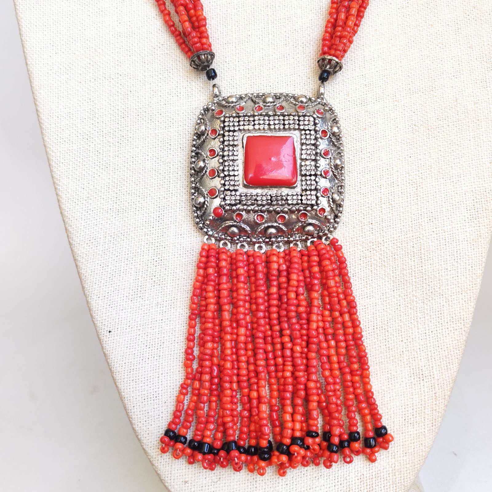 Vintage Red Faux Coral Beaded Necklace with Silver Tone Pendant and Tassel detail photograph